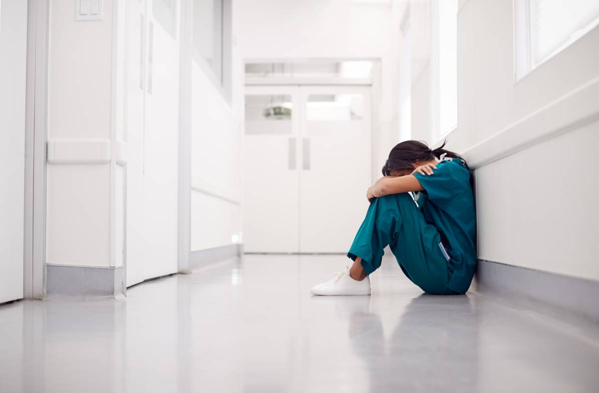 A healthcare worker sits in an empty hallway